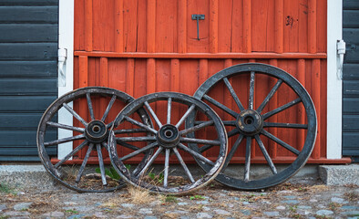 Obraz premium Old wagon wheels in front of red wooden building