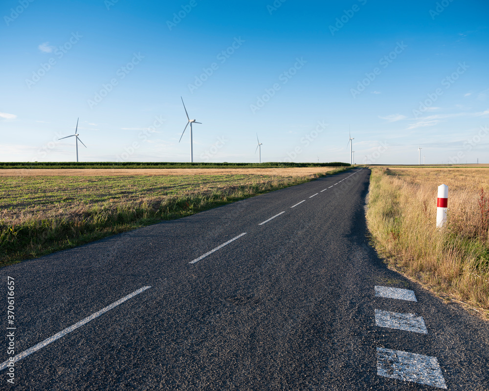 Poster road and wind turbines in rural landscape of northern france