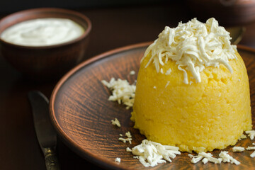 A corn porridge (mamaliga) or polenta with cheese on a dark background