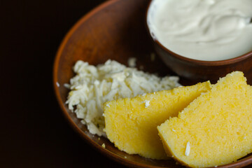 A corn porridge (mamaliga) or polenta with cheese on a dark background