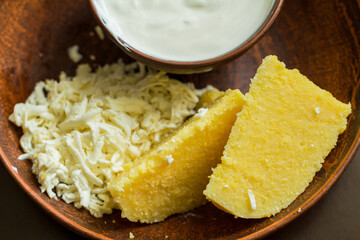 A corn porridge (mamaliga) or polenta with cheese on a dark background.