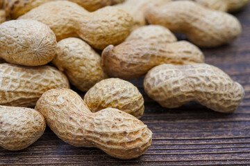 peanuts in peel texture closeup on wooden background
