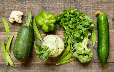 Top view set raw of green vegetables vegetarians spread on dark wooden background.