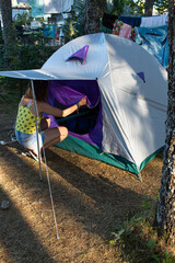 Attractive young female with a facemask opening the zip of the entrance of a tent