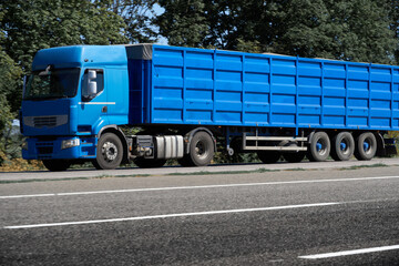 truck on the road, side view, empty space on a blue container - concept of cargo transportation, trucking industry