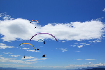 a group of paratroopers fly paragliding over the Italian Alps