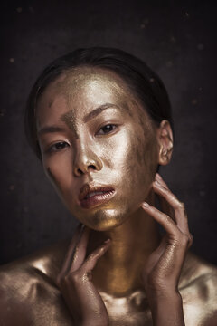 Young asian woman in golden oil paint at studio