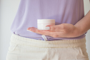  A jar of anti-aging cream is held in the hands of a woman with a beautiful manicure. Natural organic eco-friendly cosmetics for skin rejuvenation