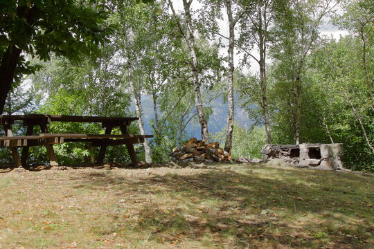 A pic nic area in the italian alps with wood table and raw stone barbeque