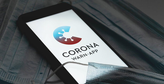 Corona Warn App logo on the screen smartphone with masks in the dark. Corona-Warn-App is a COVID-19 contact tracing application. Moscow, Russia - July 12, 2020