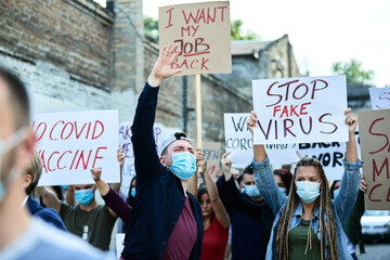 Crowd of people with protective face mask protesting on city streets during coronavirus epidemic.