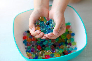 Children is hands are holding the orbeez.
