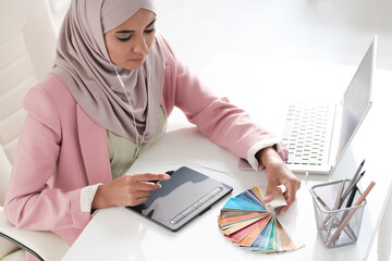 Above view of concentrated young Arabian graphic designer choosing color for design in office