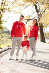 Fototapeta premium Happy young family in the autumn park. mom, dad and little daughter enjoying life together outdoors. People having fun in nature. Mother's, father's, child's day.