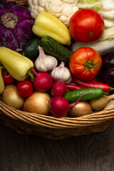Different Organic Fruits and vegetables in basket on wooden table back.
