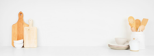 Kitchenware and utensils on a white shelf or counter. Banner with copy space against a white wall. Home kitchen cooking decor.