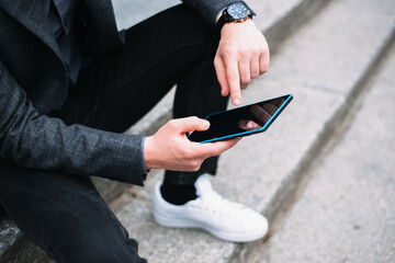 Close up photo of man in casual using tablet outdoor.