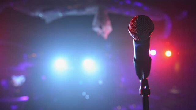 Sweeping close up of stage microphone under colorful spotlights 