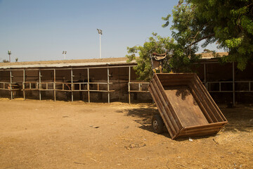 an overturned cart in an open-air stable