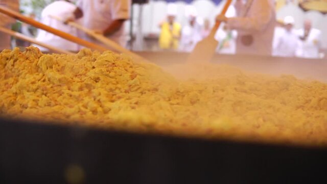 Chefs Frying an Omelette in a Giant Frying Pan with Spoons Shaped like Boat Oars