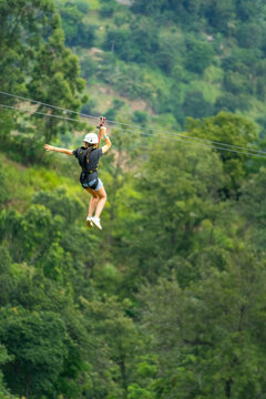 Young woman going on a zipline in the jungle. tree climbing in Sri Lanka. adventure , challenge and sport concept