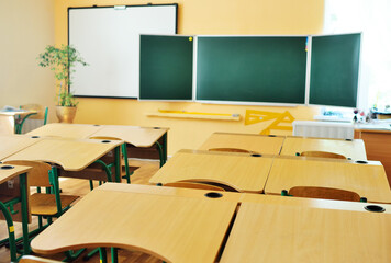 an empty schoolroom without people, a green blackboard and wooden desks with chairs-preparation for the lesson, back to school, education, Knowledge Day. Modern school interior.