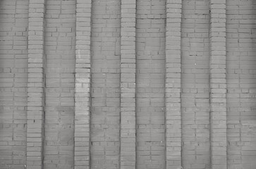 Facade of an old brick building. Gray brick wall with vertical columns. Background or texture of gray concrete  wall. Contemporary urban architecture.
