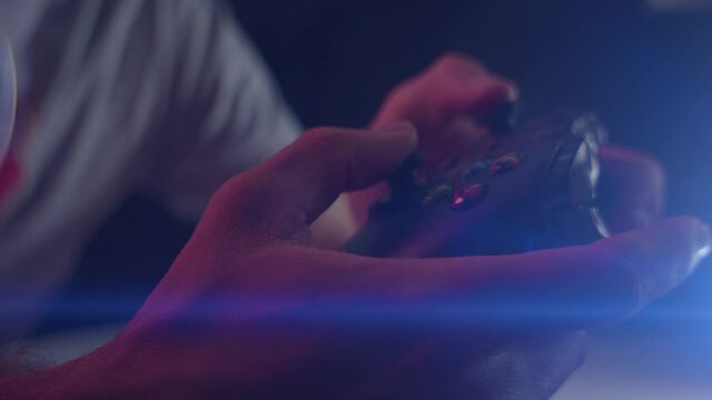 Playing video games in a darkened room with an anamorphic lens flare on a controller buttons playing quickly close up