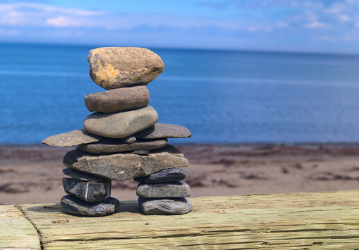 Mini Stone Inukshuk symbol made by hand with rocks, on the seashore in the bas-saint-laurent, beach of Sainte-Luce, Quebec, on a sunny summer afternoon
