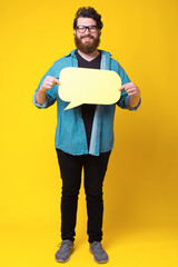 Photo of cheerful young bearded man holding speech bubble.