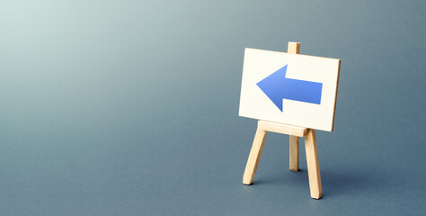 Easel with a blue left arrow. Sign of direction. Advertising of the location of a store or outlet....