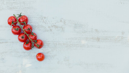 Naklejka na ściany i meble Top view of red cherry tomatoes on a light blue background. Free copy space for text