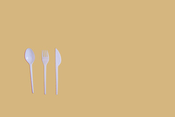 plastic spoon, fork and knife on yellow background flat lay. Horizontal image