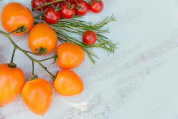 Various colorful tomatoes and rosemary herb on light blue background