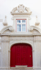 Red door on historic white building with window on top in Lisbon, Portugal