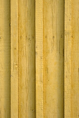 Yellow wooden background close-up. Wooden laths are yellow. Relief surface of painted wooden boards.
