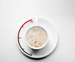 Coffee cup with fuel gauge on white saucer, isolated on white background. Top view of a hot breakfast drink.
