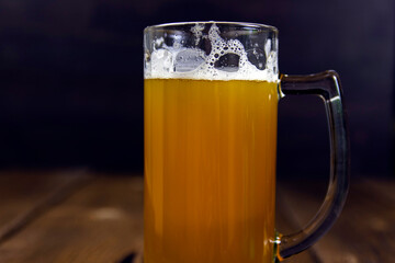 a glass of cold thick beer on a wooden table