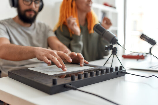 Creating sound. Close up of hands of man making music using equipment, drum pad machine. Female and male bloggers recording video blog or vlog at home