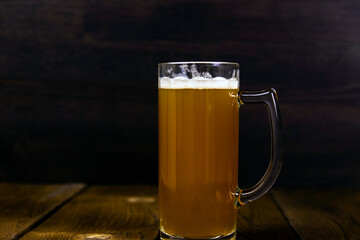 Glass of cold unfiltered thick light beer on rustic wooden table