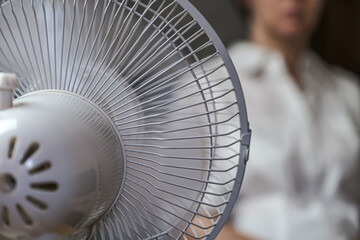 A working household fan on the table and a blurry image of the girl in the background.