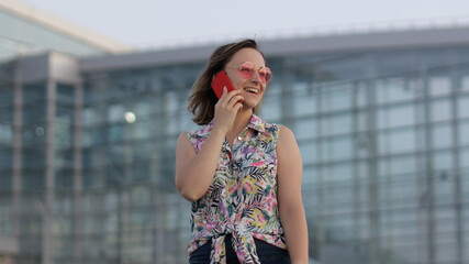 Girl in trendy sunglasses uses her phone. Using smartphone for call, talk. Vacations, tourism