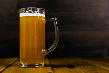 a glass of cold thick unfiltered beer on a wooden table