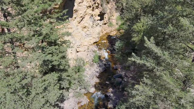 Aerial view of a babbling brook the a flight high above to see the forest and snow-capped peak in summer