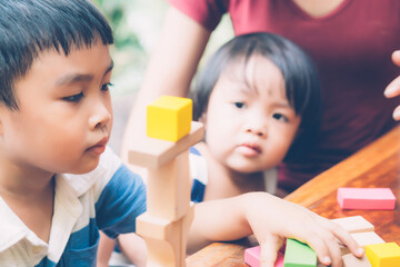 Obraz premium Family with asian mother and children playing toy block at home, mom and son and daughter doing activity and hobby about learning and development, creative and imagination, education concept.