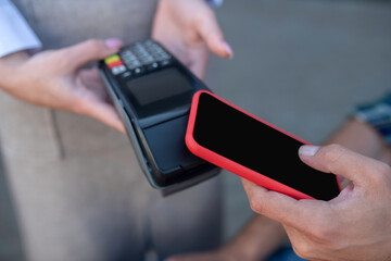 Close-up of male customer paying bill with smartphone
