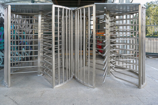 Protected entrance gate secured turnstiles outdoors. Steel revolving turnstiles at the entrance of production or metro station. Closeup of steel revolving security turnstile on the street