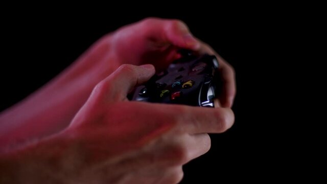 Playing video games in a darkened room with a black background close up on a controller buttons playing quickly