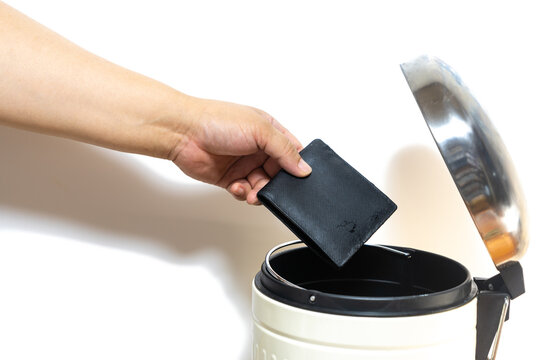man hand throws a wallet into a trash can on white background