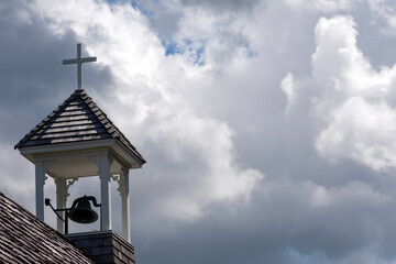 Bell tower of the church with a white cross, symbolizing Christianity and religion.